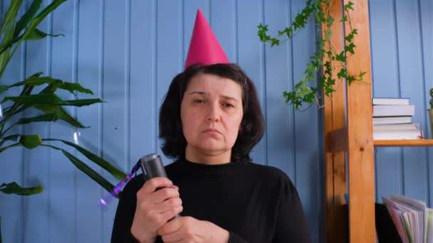 Femme des années 50 célébrant seule à la maison. Une vieille femme triste et solitaire en bonnet lançant des confettis. — Video