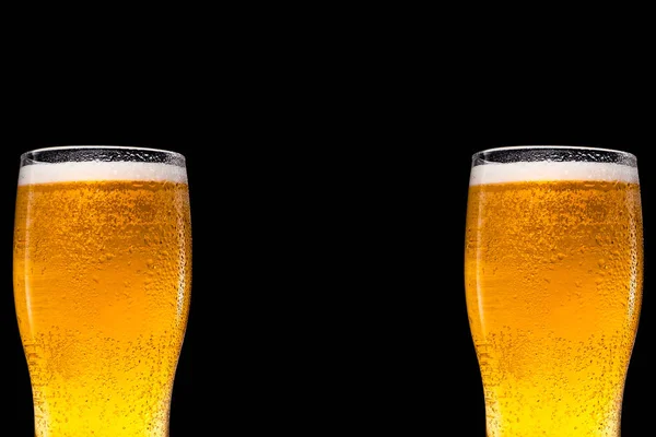 Siyah arka planda bira olan iki bira bardağı. Metin ve logo için boşluk