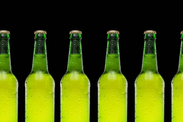 Hat sörösüveg egymás után, fekete háttérrel. Hideg és frissítő sör — Stock Fotó