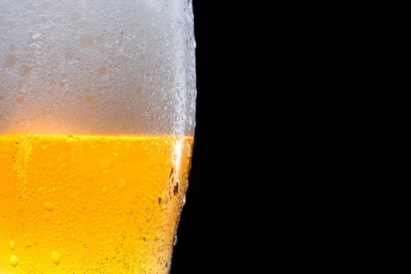 Siyah arka planda bira ve köpüklü yarım bira bardağı. Metin ve logo için boşluk.