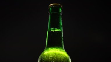 Bira şişesi koyu arkaplanda dönüyor.