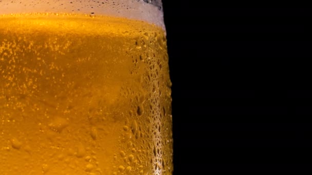 Cerveja leve fria em um copo com gotas de água gira. — Vídeo de Stock