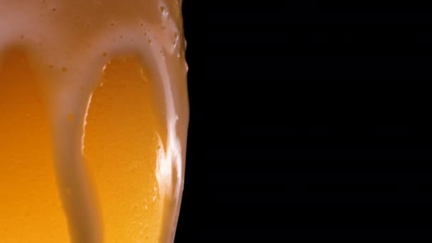 Cerveza ligera se vierte en el vidrio. Cerveza fría en un vaso con gotas de agua. Cerveza Lager formando espuma de cerca. Frescura y espuma. Fondo negro aislado. Cerveza lager de microcervecería. — Vídeos de Stock