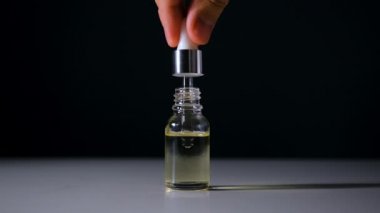 Siyah arka planda, pipetten yağ damlaları düşüyor. Pipet dikey olarak tutulur