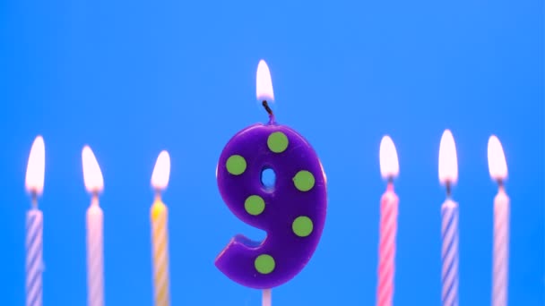 Velas de cumpleaños ardientes aisladas sobre fondo azul, número 9 — Vídeo de stock