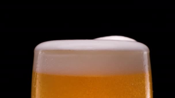 En cámara lenta. Cerveza Lager vertida con burbujas y espuma sobre fondo negro. — Vídeos de Stock