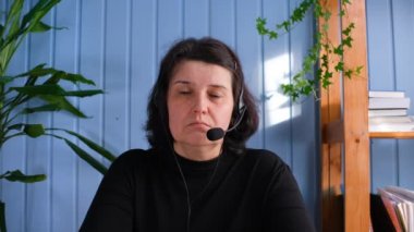 Mikrofonlu yaşlı bir kadın online görüşme yapıyor, uzaktan çalışıyor ya da iş arkadaşlarıyla projeyi tartışıyor..