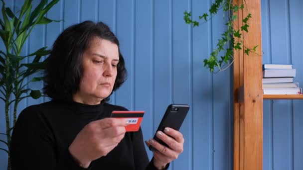 Ανώτερη κυρία που κατέχει πιστωτική κάρτα και smartphone. Ευτυχής θηλυκό αγοραστής χρησιμοποιώντας άμεση εύκολη πληρωμές για κινητά κάνοντας την αγορά στο ηλεκτρονικό κατάστημα. Υπηρεσία εφαρμογών ηλεκτρονικής τραπεζικής. Ηλικιωμένοι και σύγχρονη έννοια της τεχνολογίας — Αρχείο Βίντεο