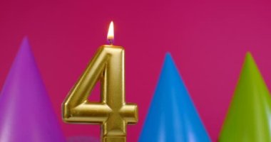 4 numaralı doğum günü pastası mumu yanıyor. Mutlu yıllar yıldönümü kutlaması konsepti. Arka planda doğum günü şapkası