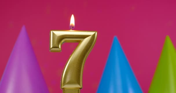 Зажигаю свечу для торта номер 7. Концепция празднования Дня Рождения. День рождения шляпа на заднем плане — стоковое видео