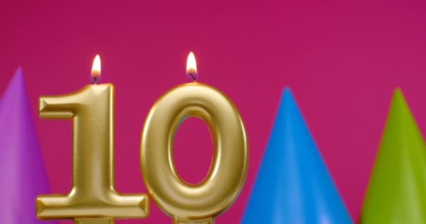 Tízes számú égő szülinapi torta gyertya. Boldog születésnapot háttér évforduló ünneplés koncepció. Születésnapi kalap a háttérben — Stock videók