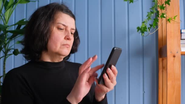 Kobieta w średnim wieku trzyma smartfona za pomocą aplikacji mobilnej. — Wideo stockowe