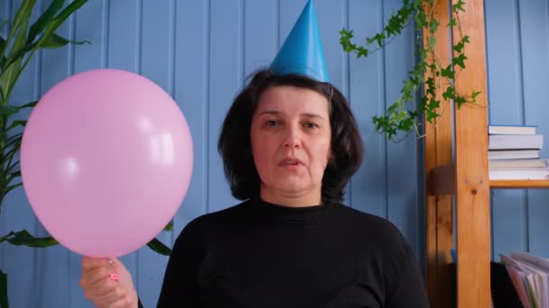 Αναστατωμένη γριά που κοιτάζει την κάμερα και κρατάει μπαλόνια, γιορτάζοντας τα γενέθλια μόνη της — Αρχείο Βίντεο