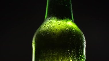 Yeşil bira şişesi dönüşümünü karanlıkta kapat. Siyah arka planda soğuk ışık ve ferahlatıcı bira.