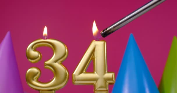 Vela de pastel de cumpleaños ardiente número 34. Feliz cumpleaños aniversario de fondo concepto de celebración. Sombrero de cumpleaños en el fondo — Vídeo de stock