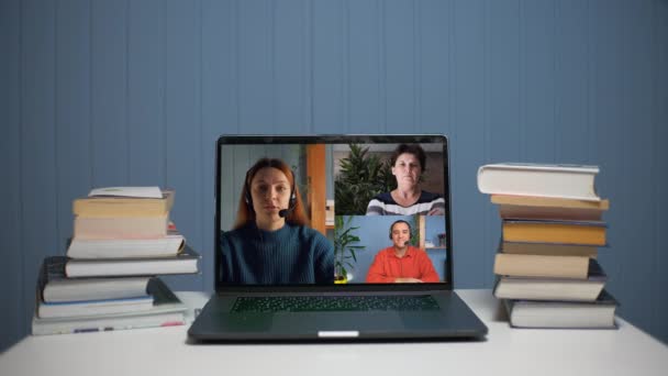 En ung kvinna pratar på ett videosamtal med en ung man och en kvinna. En ung kvinna undervisar online via videokommunikation. — Stockvideo