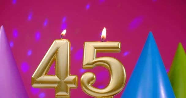 Зажигаю свечу для торта номер 45. Концепция празднования Дня Рождения. День рождения шляпа на заднем плане — стоковое видео