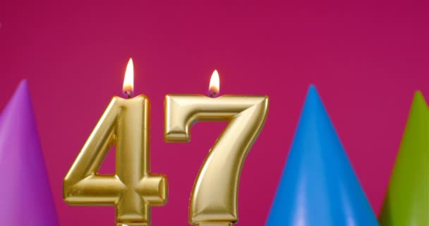 Burning birthday cake candle number 47. Happy Birthday background anniversary celebration concept. Birthday hat in the background — Stock Video