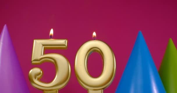 Bränner födelsedagstårta ljus nummer 50. Grattis på födelsedagen bakgrund jubileum firande koncept. Födelsedag hatt i bakgrunden — Stockvideo