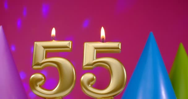 Burning birthday cake candle number 55. Happy Birthday background anniversary celebration concept. Birthday hat in the background — Stock Video