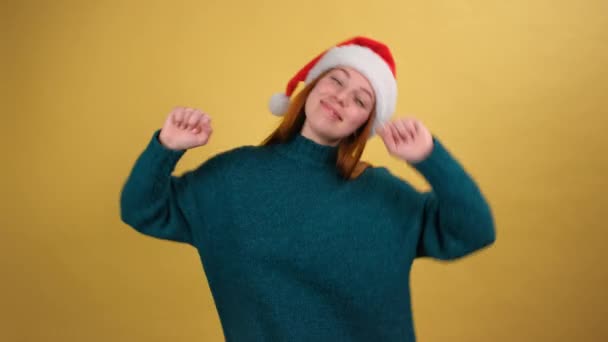 Милая молодая женщина в смешной шляпе Санта-Клауса поет колокольчики и танцует — стоковое видео