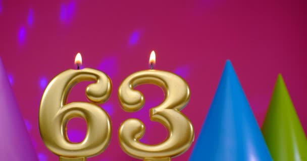 Burning birthday cake candle number 63. Happy Birthday background anniversary celebration concept. Birthday hat in the background — Stock Video