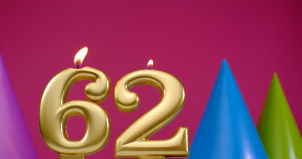 Палаюча свічка для торта на день народження No 62. З днем народження концепція святкування дня народження. День народження капелюх на задньому плані — стокове відео
