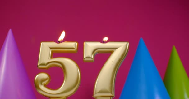 Зажигаю свечу для торта номер 57. Концепция празднования Дня Рождения. День рождения шляпа на заднем плане — стоковое видео