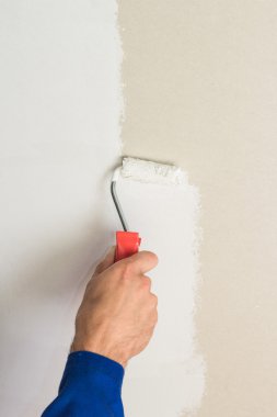 Duvardaki boya silindiri kullanan adam