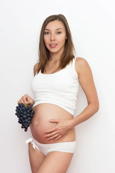 Беременная женщина с виноградом — стоковое фото