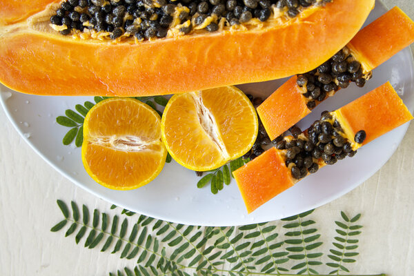 Sweet papaya and tangerine on a plate in natural light