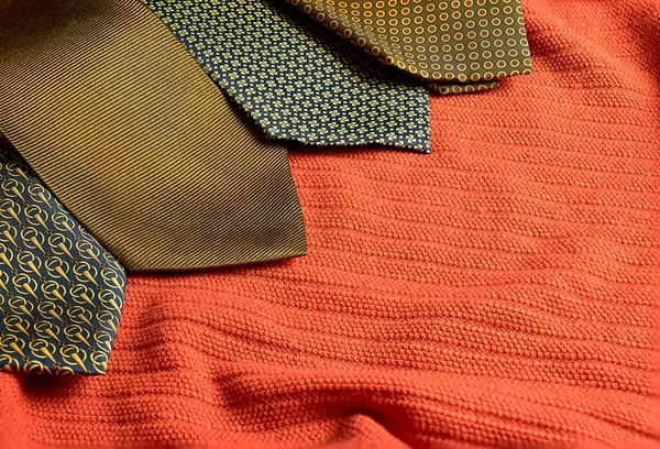 Turuncu bir yüzeyde birkaç altın desenli kravat.