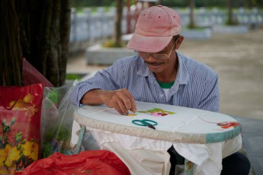 Tam Coc, Vietnam - 01 Mart 2020: Yerel bir sanatçı beyaz bir tuvale bir tablo nakışlıyor