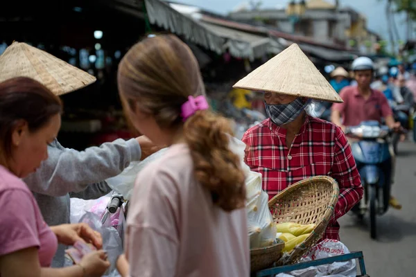 Hoi An, Vietnam - 05 Mart 2020: Yaşlı Vietnamlı bir kadın pazarda yiyecek satıyor