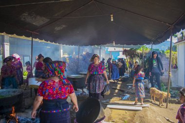 Tipik Maya kıyafetleri içinde yerli kadınlar partide yemek pişiriyor.
