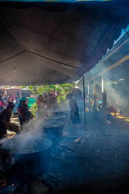 Tipik Maya kıyafetleri içindeki yerli kadınlar partide küvetlerle yemek pişiriyorlar.