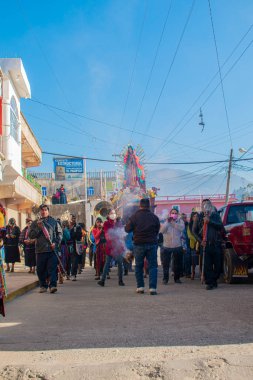 Mavi gökyüzü dumanlı Guadalupe bakiresi resmi olan insanlar.
