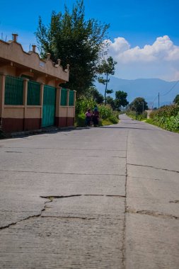 Arka planda dağlar ve yürüyen insanlar olan yolun hemros manzarası.