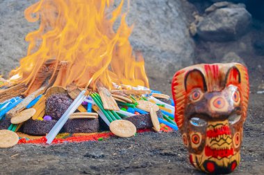 Renkli hayvan şeklinde ahşap çiğnenmiş, arkasında Maya seremonisi var.