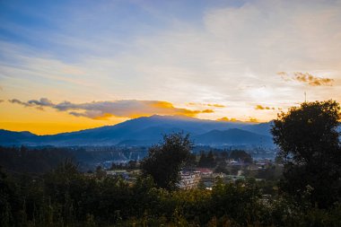 Uzaklardan ve güzel günbatımından dağlar ekiyorsun.