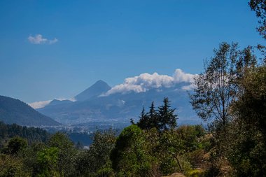 Ağaçlı ve bulutlu bulutlar arasındaki volkan manzarası