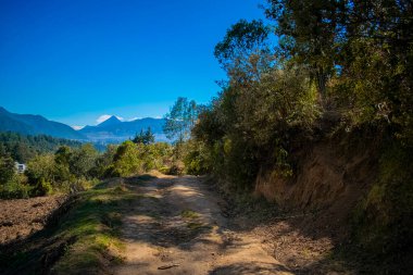 Mavi gökyüzü ve uzaktaki volkanın manzarasıyla vadiye giden güzel bir yol.