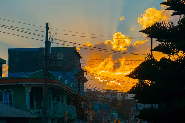Sylwetka Domu Mieście Zachodem Słońca Tle Żółtymi Chmurami Promieniami Słońca — Zdjęcie stockowe