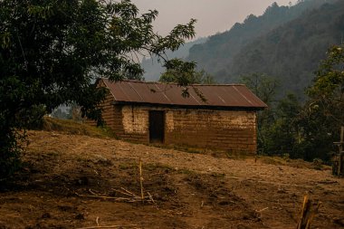 Arka planda ormanlı, gün batımlı eski kerpiç evi.