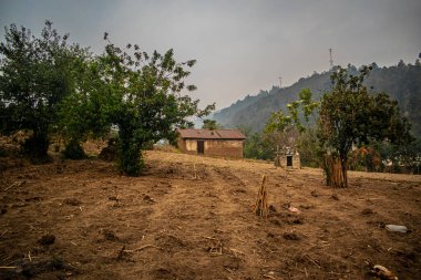 Kuru tarlanın ortasında gün batımlı bir ev.