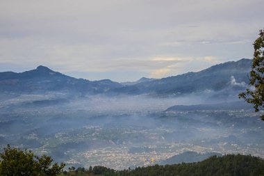 Güneşin doğuşunda şehrin üzerinde bulutlarla vadiyi nefes kesen manzara.