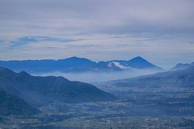 Dağlar ve sisler arasında gün doğumu manzarası yükseliyor