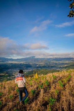 Çocuk tarlada yürüyor bulutlu vadi manzarasıyla