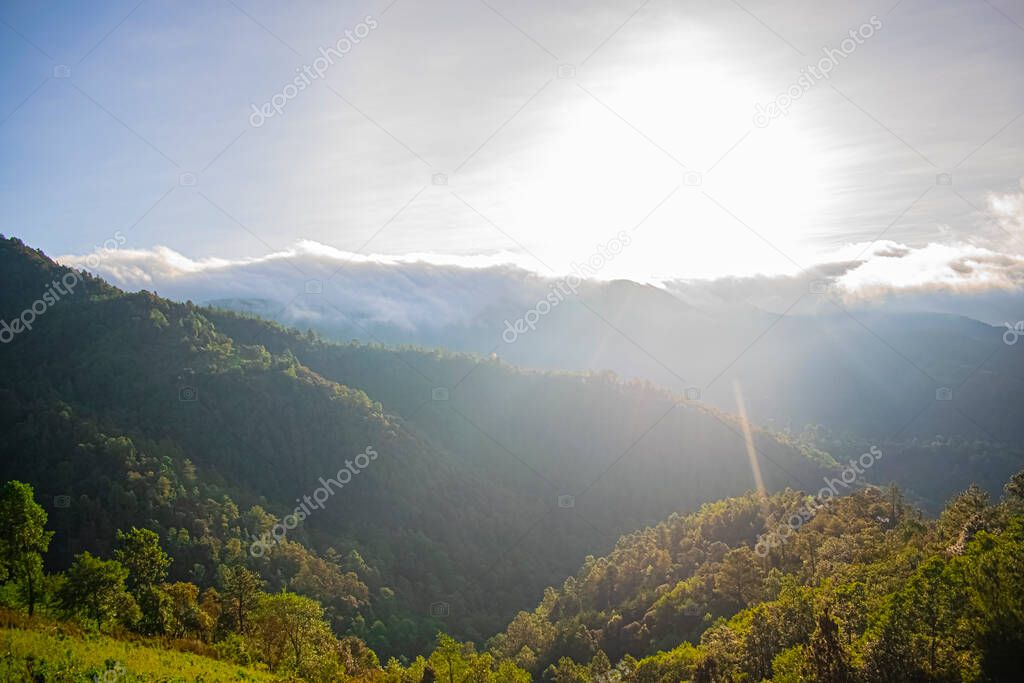 sun shining on the mountains with clouds and forest in cajola