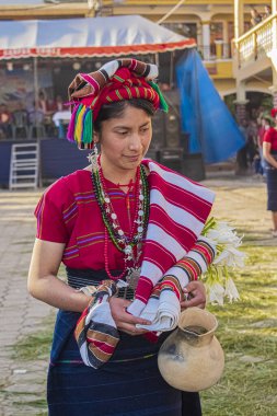 Antik kolyelerle elinde çiçeklerle dans eden kadın.